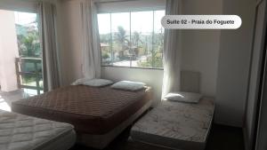 a small bedroom with two beds and a window at Praia do Foguete - Aluguel Econômico in Cabo Frio