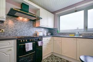 a kitchen with white cabinets and a stove top oven at 2 Bed Apartment near Belfast & Ferry in Belfast