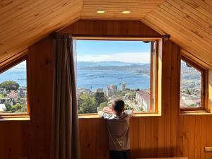 a man standing in front of a window looking out at the water at Hotel Faro Azul Valparaíso Cerro Alegre in Valparaíso