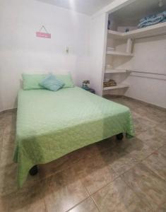 a bedroom with a bed with a green comforter at A pasos playa olas altas, Faro y Machado in Mazatlán