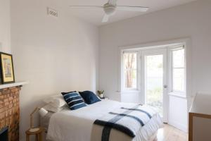 een witte slaapkamer met een bed en een raam bij Relax by the Sea in Queenscliff