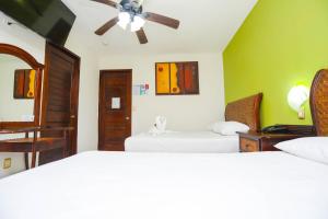 a bedroom with two beds and a ceiling fan at Hotel Parador in Canc&uacute;n