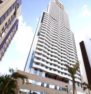 un edificio alto con palmeras delante en Apartamento Mondial Salvador, en Salvador