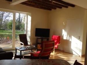 a living room with red chairs and a television at Charmante Ferme Rénovée avec Terrasse à 7 km du Mans, 8 Couchages, TV, Internet, Cuisine Équipée - FR-1-410-254 in La Bazoge +1 photo