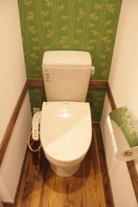 a white toilet in a bathroom with green wallpaper at 【都電屋203】标准间/都电荒川线/近三ノ輪/一线直达秋叶原/上野/浅草 in Tokyo