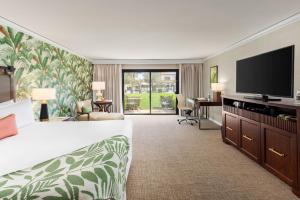 インディアン・ウェルズにあるTommy Bahama Miramonte Resort & Spaのベッド1台、薄型テレビが備わるホテルルームです。