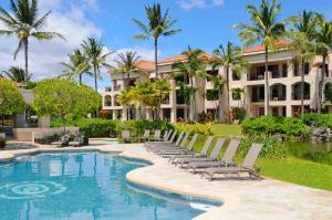 a resort pool with chaise lounge chairs and palm trees at Shores at Waikoloa 301 - MCH in Waikoloa