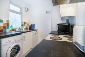 a kitchen with a washing machine and a microwave at House Close to City Centre and City Airport in Belfast
