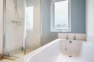 a white bath tub in a bathroom with a window at House Close to City Centre and City Airport in Belfast