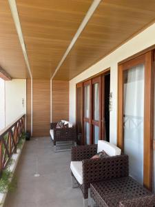 eine Veranda mit Sofas und Stühlen auf einem Balkon in der Unterkunft Casa beira lagoa barra de São Miguel in Barra de São Miguel
