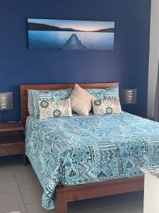 1 dormitorio con 1 cama con pared azul en Marina Views Apartment Cullen Bay en Larrakeyah