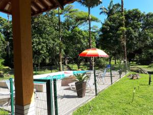 a patio with an umbrella next to a pool at Chacara Salmo 27 in Antonina