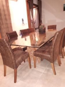 a dining room table with chairs and a glass top at Chacara Salmo 27 in Antonina