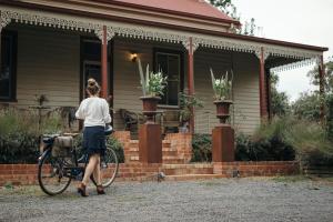 Una mujer caminando en bicicleta delante de una casa en Summerlands - Country Luxe, en Alexandra