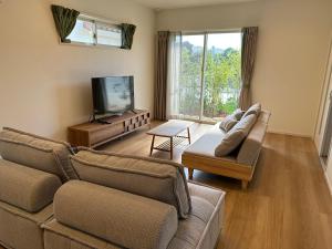 a living room with two couches and a flat screen tv at ベアーズステイ久米島ヴィラ in Kumejima