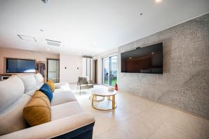 a living room with a couch and a tv on a wall at Cherryblossom in Changwon