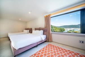 a bedroom with two beds and a large window at Cherryblossom in Changwon