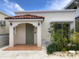 una casa blanca con una puerta verde en ベアーズステイ久米島ヴィラ, en Kumejima