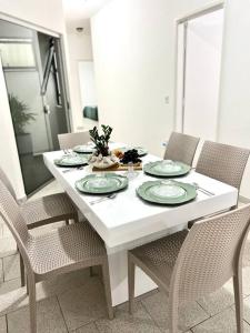 a white dining room table with chairs and plates on it at Acolhedora casa de 03 quartos in Passos