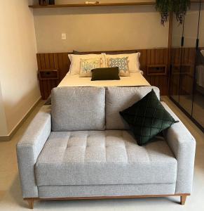 a bed with a couch with a laptop on it at Conforto e sofisticação studio 1104, centro de JF in Juiz de Fora