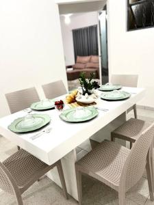 uma mesa branca com quatro cadeiras e pratos em Acolhedora casa de 03 quartos em Passos