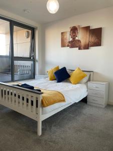 1 dormitorio con 1 cama con almohadas amarillas y azules en Wembley Stadium Luxurious Apartment, en Londres