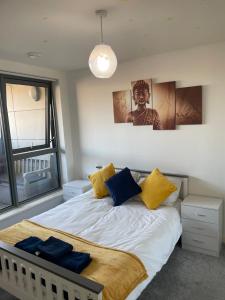 1 dormitorio con 1 cama con almohadas amarillas y azules en Wembley Stadium Luxurious Apartment, en Londres