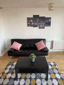 sala de estar con sofá de cuero negro y almohadas rosas en Wembley Stadium Luxurious Apartment, en Londres