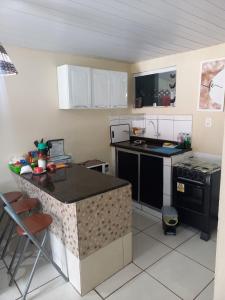 a kitchen with white cabinets and a black stove at Condomínio da Barra - Chalé 6B in Tamandaré