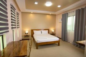 ein Schlafzimmer mit einem Bett, zwei Lampen und einem Fenster in der Unterkunft Dancels Inn in Ormoc City
