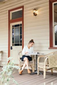 Eine Frau, die an einem Tisch auf einer Veranda sitzt. in der Unterkunft Summerlands - Country Luxe in Alexandra