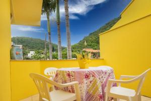 una mesa con un jarrón de flores en un balcón amarillo en Apartamentos Villa Porto do Sol, en Bombinhas