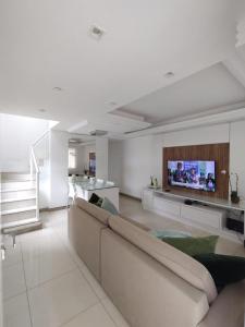 een woonkamer met een bank en een flatscreen-tv bij Village Praia Dourada - Praia dos Milionários in Ilhéus