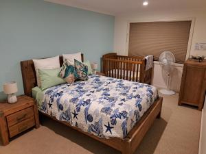 a bedroom with a bed with a blue and white comforter at Paradise by the Bay in Callala Bay