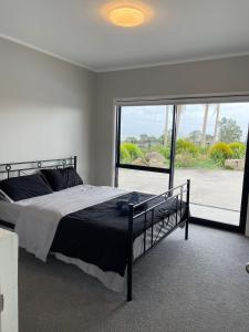 une chambre avec un lit et une grande fenêtre dans l'établissement franklin chapel, à Clarks Beach