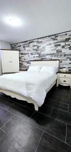 sypialnia z dużym białym łóżkiem i ceglaną ścianą w obiekcie Superbe propriété moderne en nature w mieście Sainte Brigitte de Laval