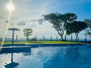 a swimming pool with an umbrella next to a fence at Ecohotel La Reserva in Piojó