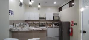 a kitchen with white cabinets and a stainless steel refrigerator at La casita Azul - Río Mar - Iquitos in Iquitos