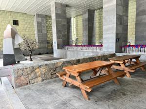 2 mesas de picnic de madera frente a un edificio en J-Grand Hotel, en Jeju