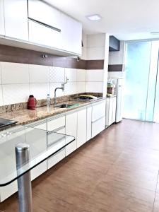 a kitchen with white cabinets and a wooden floor at Excelente casa a 3km do centro de Itabira in Itabira