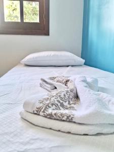 a white bed with a blanket on it with a window at Excelente casa a 3km do centro de Itabira in Itabira
