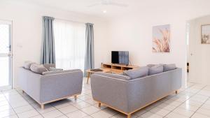 uma sala de estar com dois sofás e uma televisão em Palm View Holiday Apartments em Bowen
