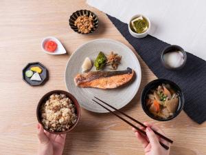 東京的住宿－千禧 三井花園飯店 東京 / 銀座，一张桌子,上面有盘子食物,还有人拿着筷子