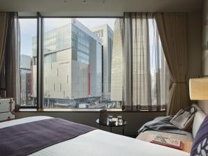a bedroom with a large window with a view of a city at Millennium Mitsui Garden Hotel Tokyo - Ginza in Tokyo