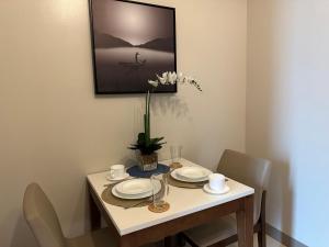una mesa de comedor con platos y un jarrón de flores en Executive Suite in Bonifacio Global City, en Manila