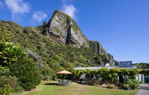 a building with an umbrella in front of a mountain at Cliffscapes in Punakaiki