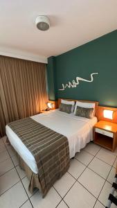 a bedroom with a large bed with a green wall at Praia do Canto Apart Hotel quarto sala varanda - andar alto in Vitória