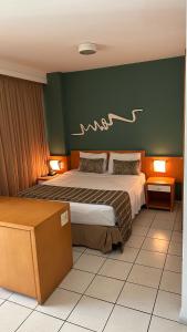 1 dormitorio con 1 cama grande y pared verde en Praia do Canto Apart Hotel quarto sala varanda - andar alto, en Vitória