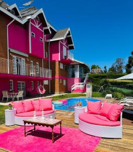 une maison rose avec des meubles roses et une piscine dans l'établissement Pousada Pink Village, à Campos do Jordão