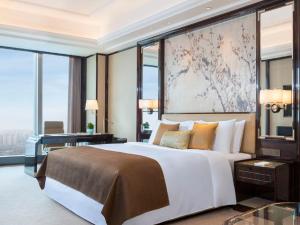 a bedroom with a large bed and a desk and windows at The St. Regis Changsha in Changsha